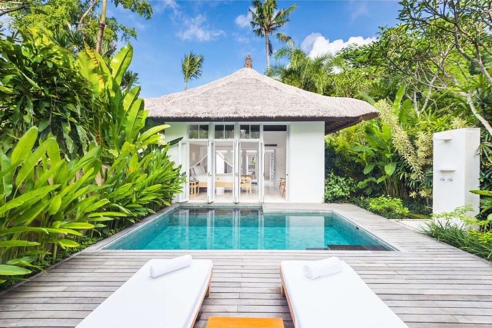 Poolside area with a thatched-roof structure in tropical gardens