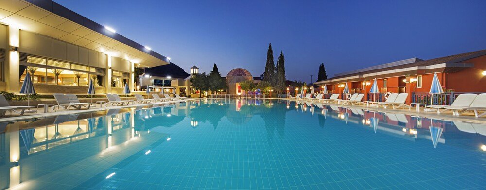 Swimming pool with lounge chairs and umbrellas at Spa Hotel Colossae Thermal