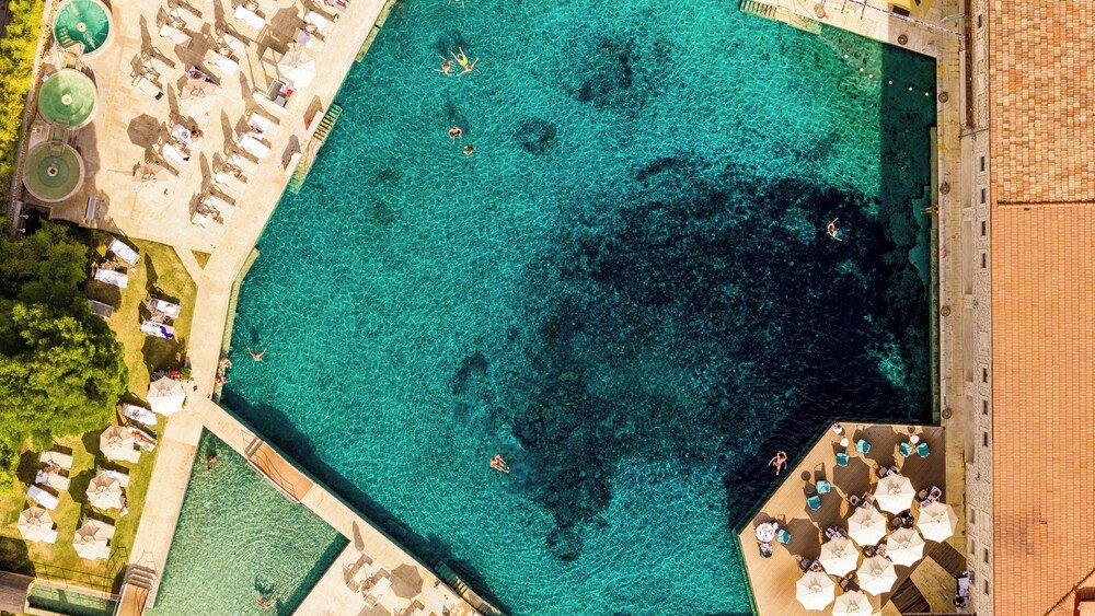 Aerial view of a large clear blue pool surrounded by sun loungers